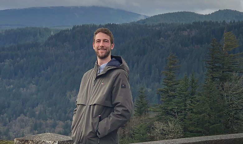 Alec Schnabel standing in front of a vista of evergreen-covered hills